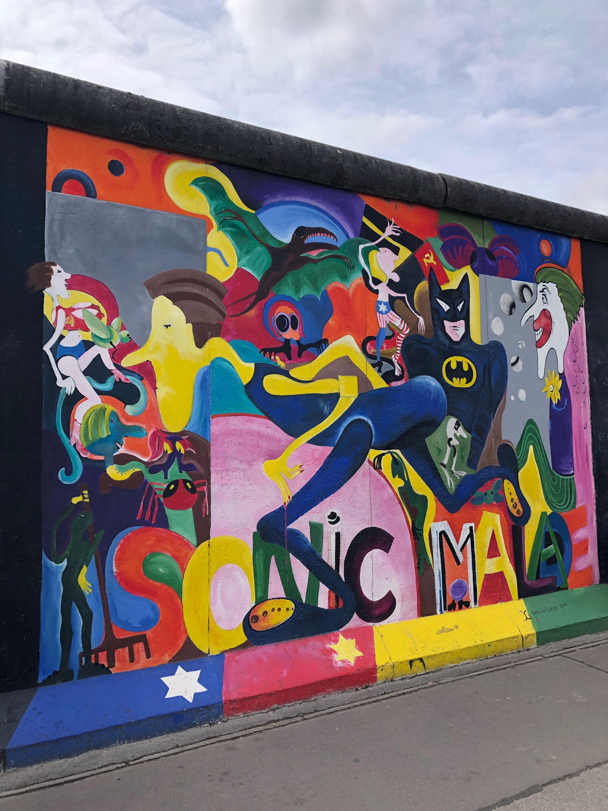 A colorful East Side Gallery mural combining Batman and other comic-style characters