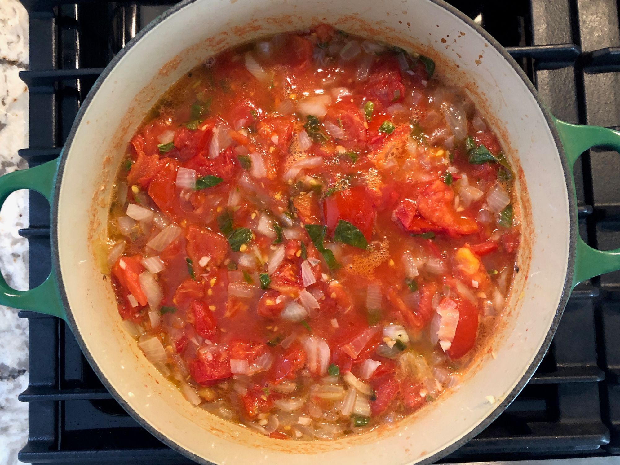 Tomatoes simmering with diced onion and basil