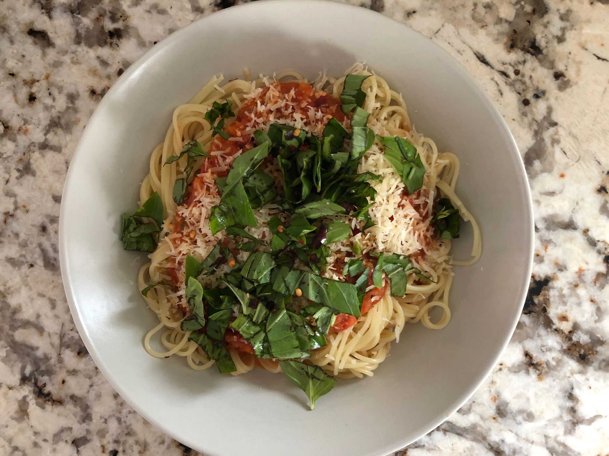 Spaghetti topped with fresh tomato sauce, grated cheese, and basil