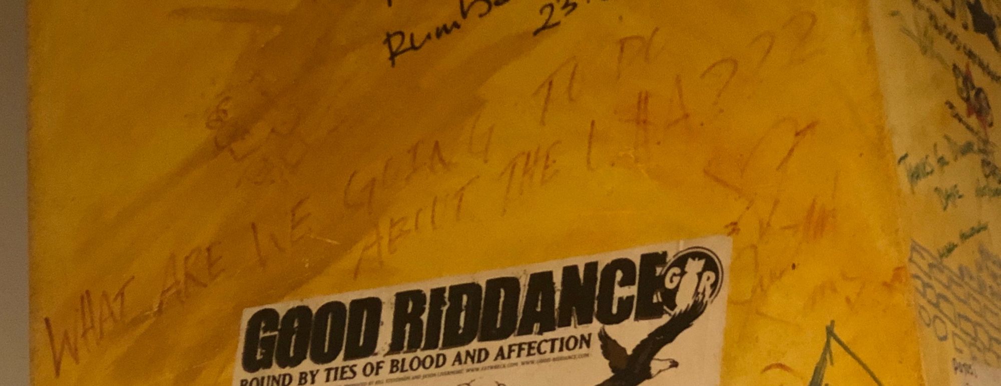 A yellow graffiti-covered wall in Berlin with a Good Riddance poster
